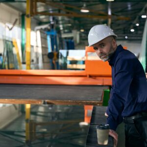 Foreman in safety helmet at workplace in window production facility