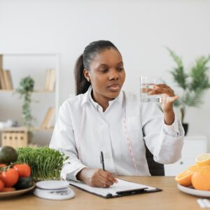 Nutrition specialist checking fluid in glass at workplace