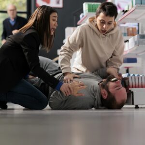 Women standing on knees near unconscious man with epilepsy